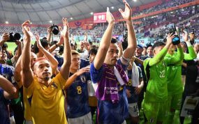 Los jugadores japoneses celebran ante su afición la clasificación a octavos de final tras vencer a España.