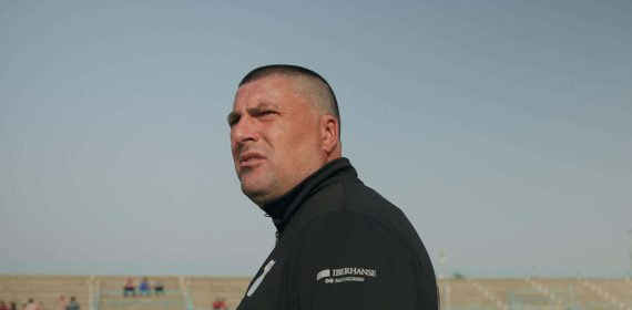 Un hombre con chándal negro observa desde la banda de un campo de fútbol