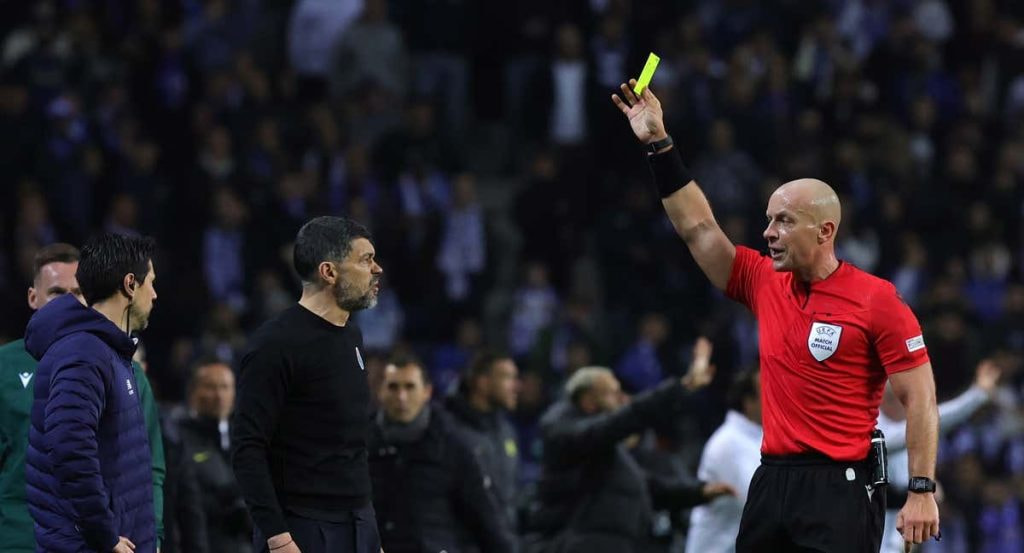 Szymon Marciniak muestra tarjeta amarilla en un partido de Champions League.