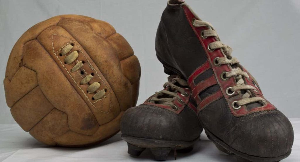 Un balón y botas de fútbol antiguos.