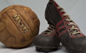 Un balón y botas de fútbol antiguos.