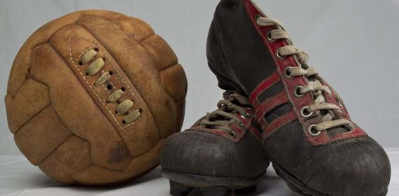 Un balón y botas de fútbol antiguos.