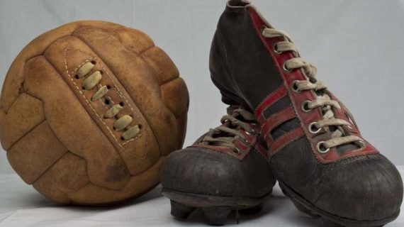 Un balón y botas de fútbol antiguos.