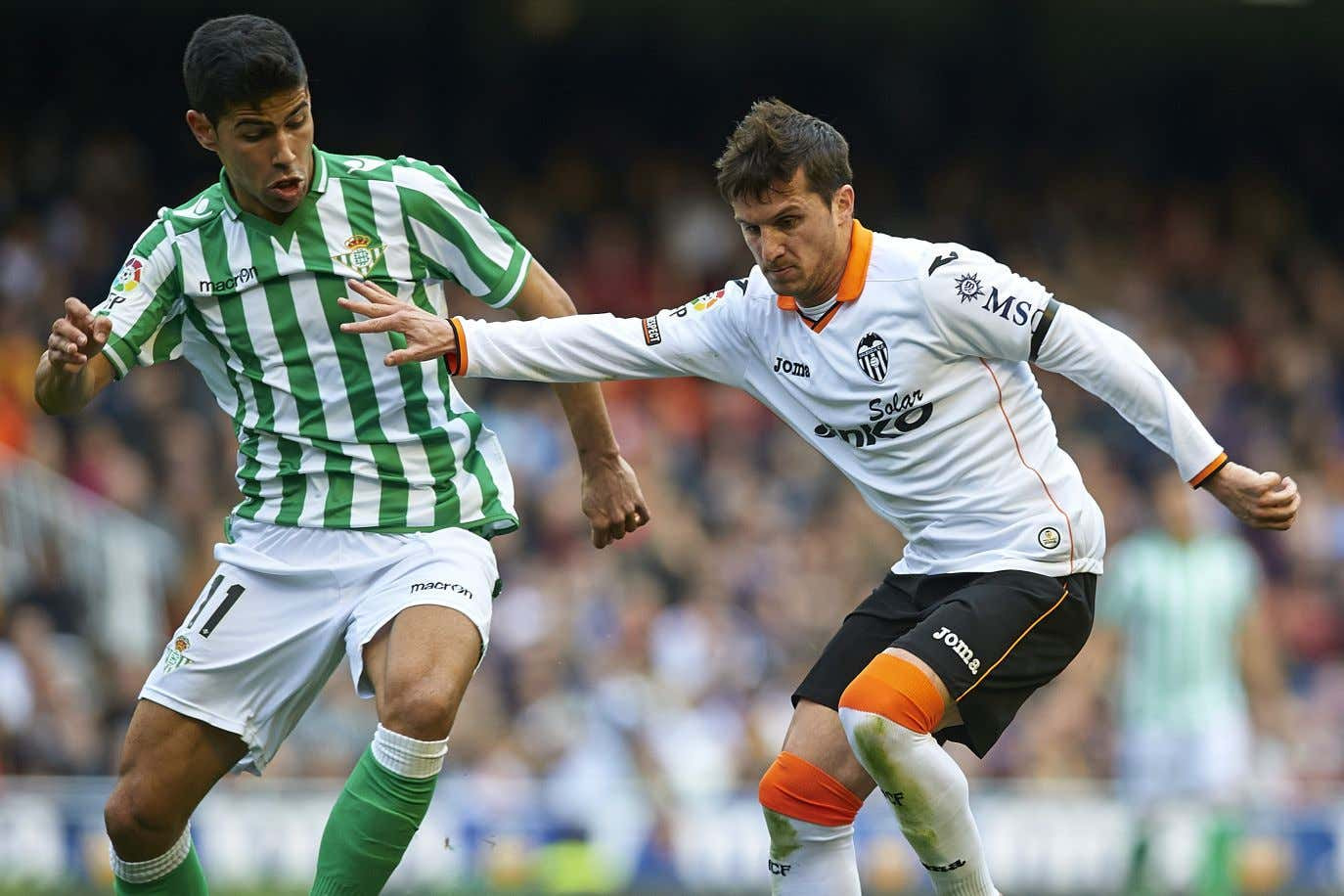 Un jugador del Real Betis disputa el balón con un futbolista del Valencia