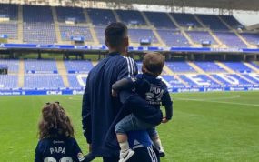 Juanfran, de espaldas en el césped del Carlos Tartiere, sostiene a sus dos hijos; uno viste una camiseta con el dorsal 'Papá'