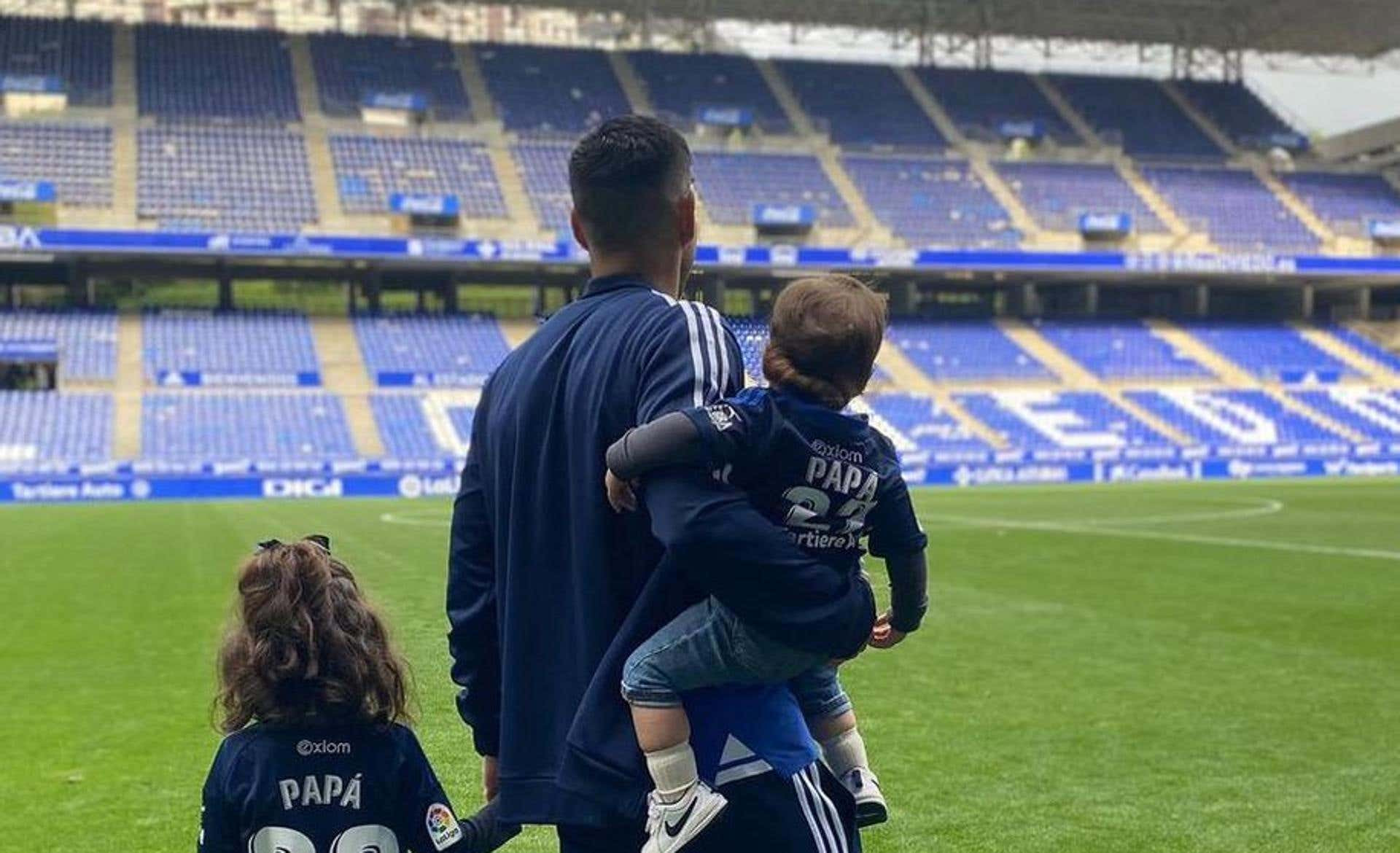 Un futbolista, de espaldas y con sus dos hijos, contempla el estadio vacío del Real Oviedo
