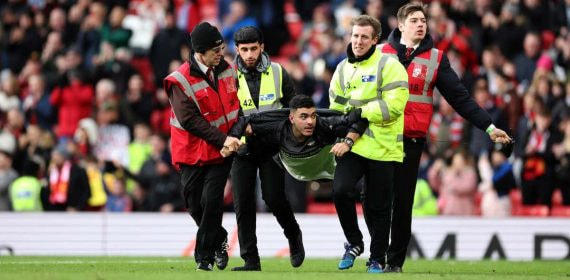 Los 'stewards' se llevan a un espontáneo en un partido de la Premier League.