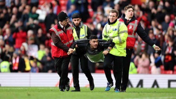 Los 'stewards' se llevan a un espontáneo en un partido de la Premier League.