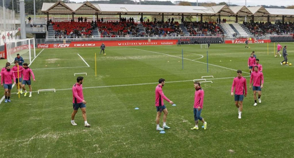 Los jugadores realizan ejercicios en el campo 2, con muchas calvas y arena.