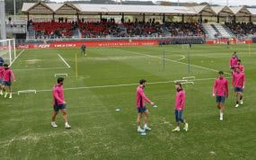 Los jugadores realizan ejercicios en el campo 2, con muchas calvas y arena.