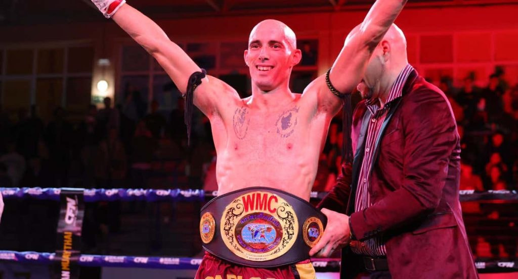 Carlos Coello festeja su victoria sobre Raksapa mientras le colocan el Campeonato del Mundo WMC.