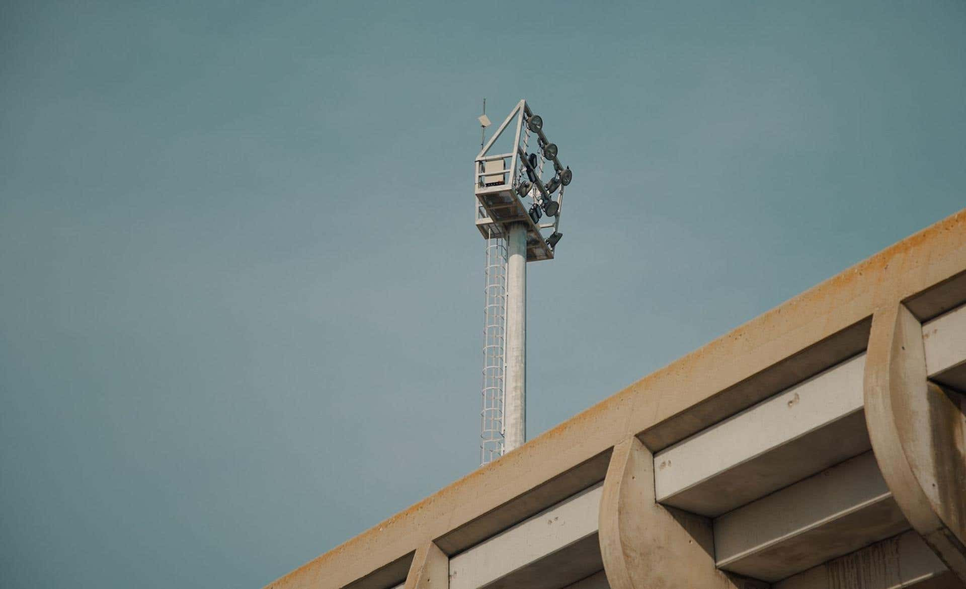 Torre de focos sobre la grada de un estadio recortada contra el cielo