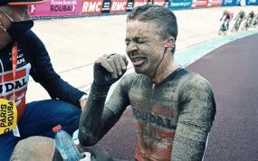 Un ciclista, cubierto de barro y agotado, tras finalizar la París-Roubaix