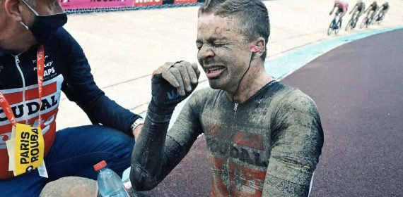 Un ciclista, cubierto de barro y agotado, tras finalizar la París-Roubaix