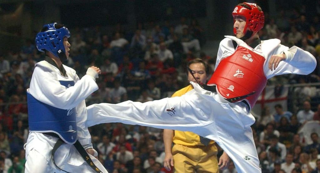 Un taekwondista recibe una patada en una competición.
