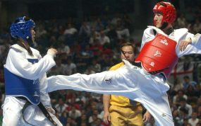 Un taekwondista recibe una patada en una competición.
