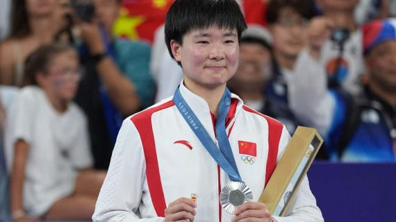He Binjiao, con su medalla de plata y su pin de España en memoria de Carolina Marín, lesionada en la semifinal.