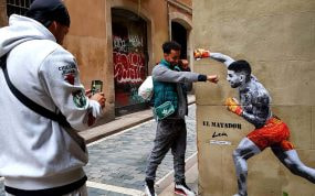 Unos paseantes se fotografían con el mural de Ilia Topuria en el barrio de Born, en Barcelona.