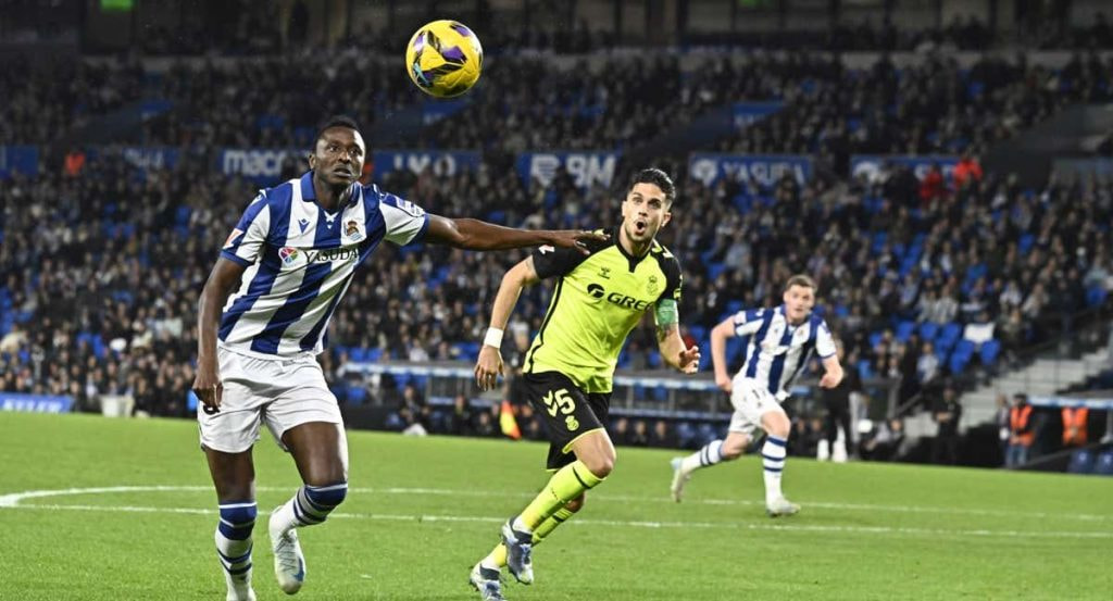 Sadiq se dispone a rematar un balón ante la atenta mirada de Bartra en un Real Sociedad-Betis.