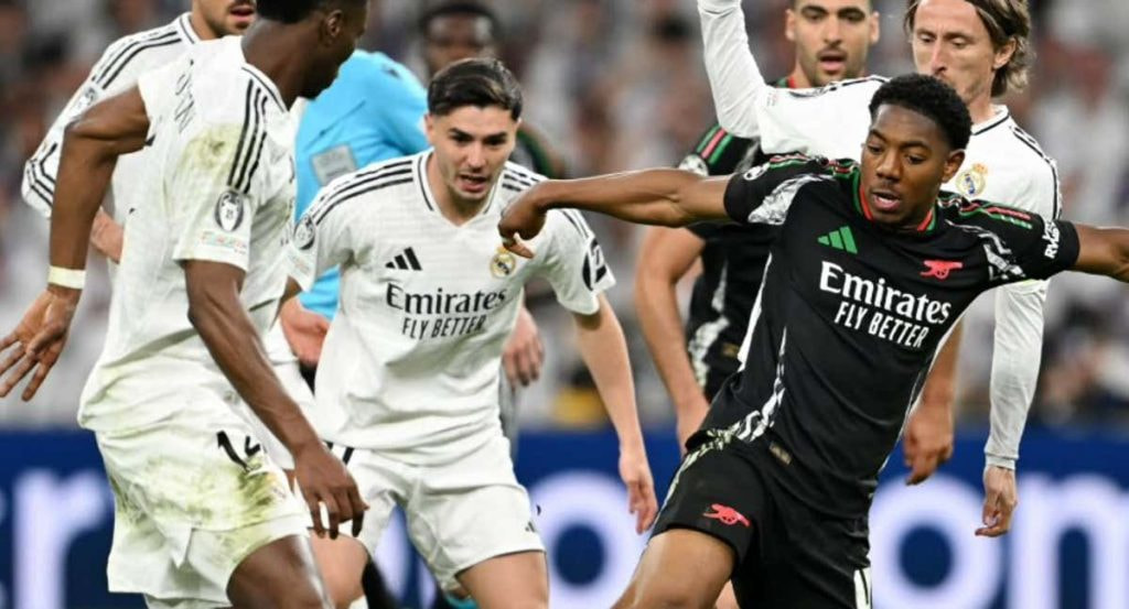 Lewis-Skelly controla un balón entre los futbolistas del Real Madrid.