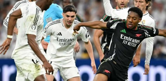 Lewis-Skelly controla un balón entre los futbolistas del Real Madrid.