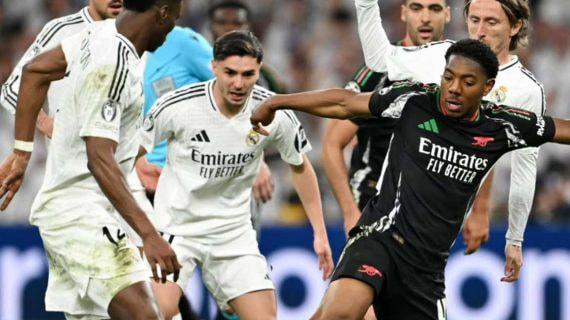 Lewis-Skelly controla un balón entre los futbolistas del Real Madrid.
