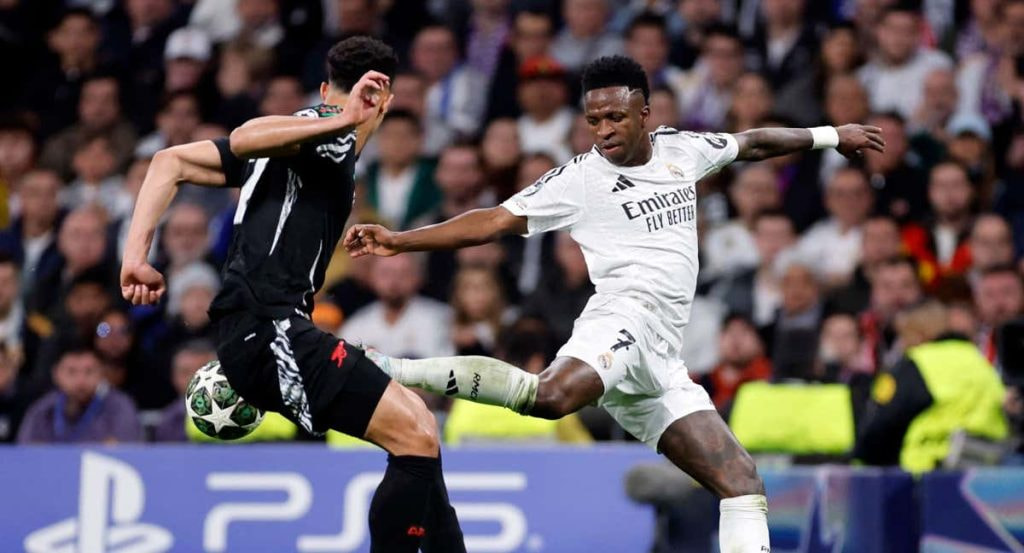 Vinicius intenta marcharse de Saliba en el Bernabéu.