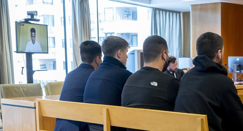 Los radicales del Atlético acusados con Vinicius testificando de fondo.
