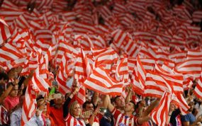 La afición del Atlético de Madrid canta el himno.