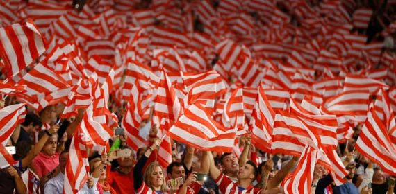 La afición del Atlético de Madrid canta el himno.