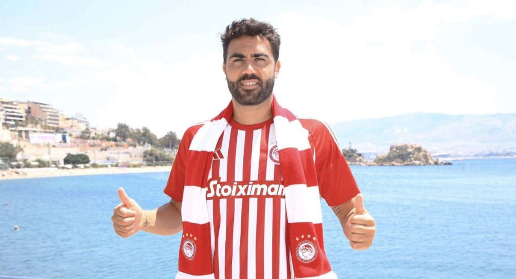 Vicente Iborra posa con la camiseta y la bufanda del Olympiacos junto al mar