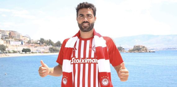 Vicente Iborra posa con la camiseta y la bufanda del Olympiacos junto al mar