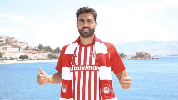 Vicente Iborra posa con la camiseta y la bufanda del Olympiacos junto al mar