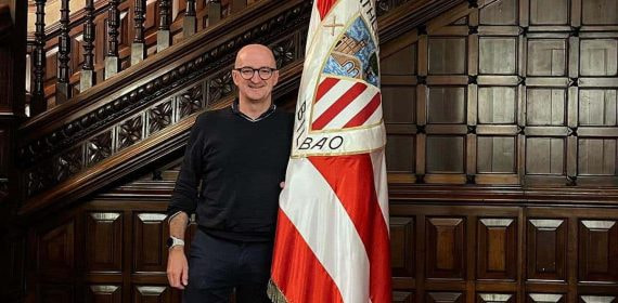 Iñigo San Millán posa junto a la bandera del Athletic de Bilbao en la sede del club.
