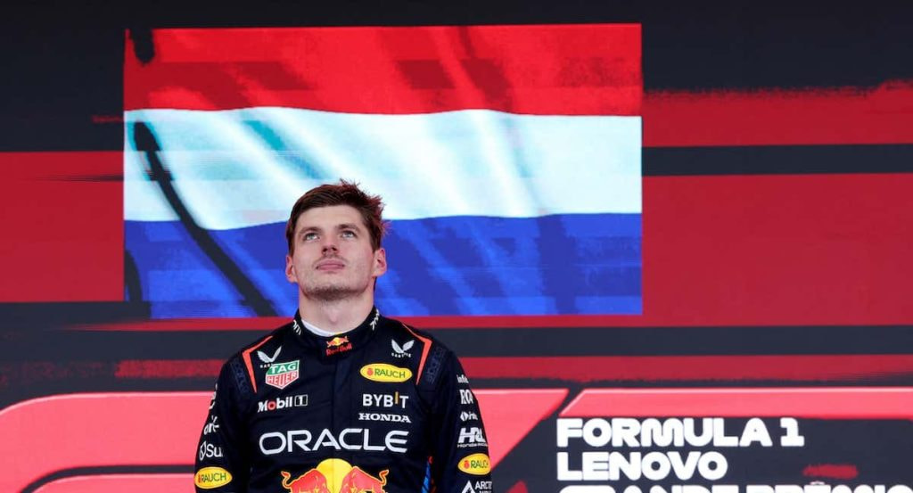 Max Verstappen en el podio junto a la bandera de los Países Bajos.