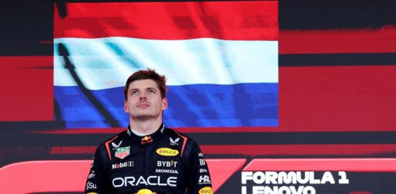 Max Verstappen en el podio junto a la bandera de los Países Bajos.