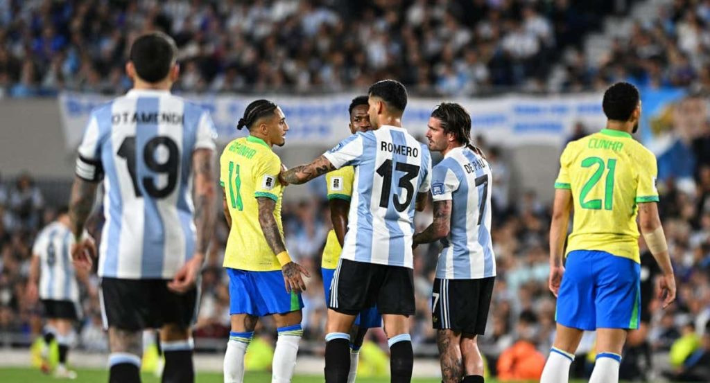 Raphinha y De Paul hablan durante el partido.
