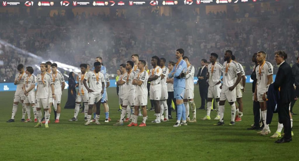 Los jugadores del Real Madrid ven como el Barcelona levanta la Supercopa.