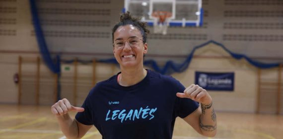 Laura Nicholls sonríe señalando la camiseta del Baloncesto Leganés en el pabellón
