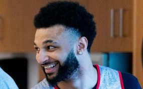 Jamal Murray sonríe en un vestuario con el logo de los Toronto Raptors al fondo