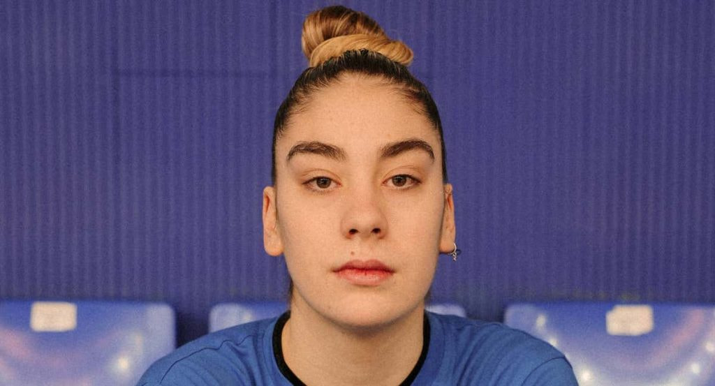 Primer plano de Paula Saravia, con moño y camiseta azul, mirando a cámara