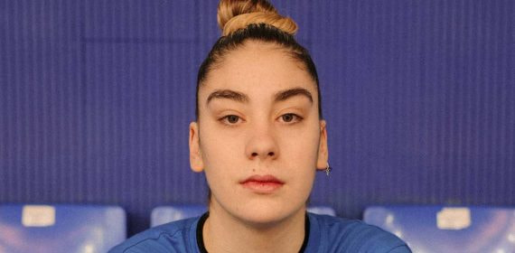 Primer plano de Paula Saravia, con moño y camiseta azul, mirando a cámara