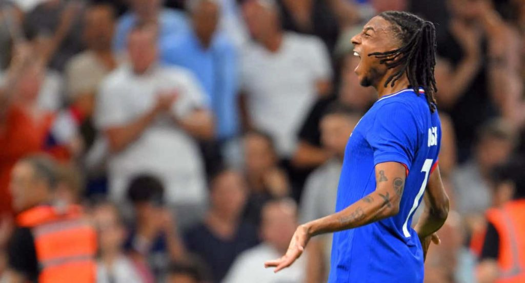 Michael Olise grita para celebrar un gol con la camiseta azul de Francia