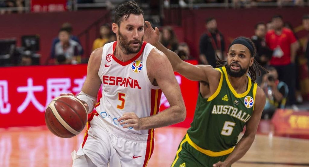 Rudy Fernández conduce el balón con España perseguido por Patty Mills, con el 5 de Australia