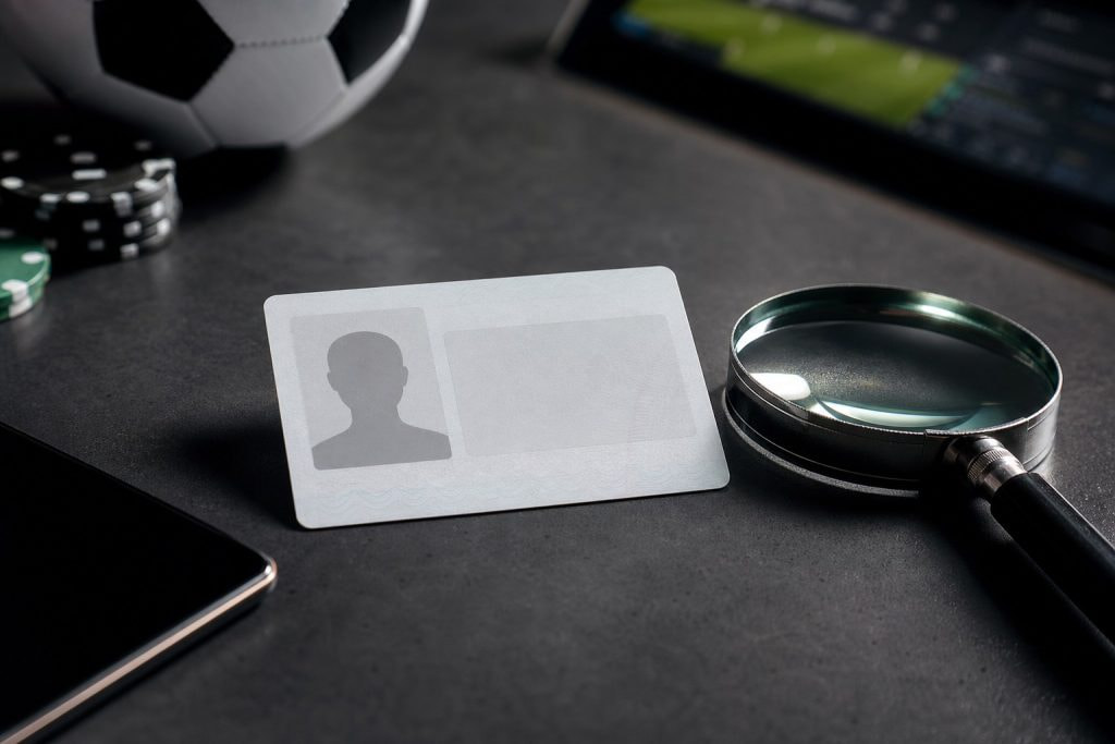 Documento de identidad y lupa que ilustran la verificación KYC en las casas de apuestas con retiro inmediato