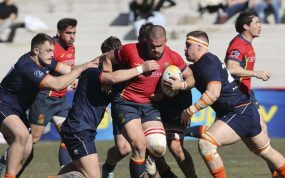 Un delantero de la selección española de rugby avanza con el balón intentando romper varios placajes
