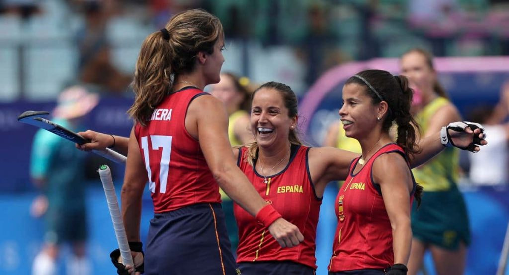 Tres jugadoras de la selección española de hockey hierba se abrazan sonrientes tras un gol ante Australia