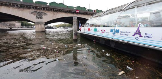 Restos de basura flotan en el Sena junto a un barco turístico bajo un puente de París