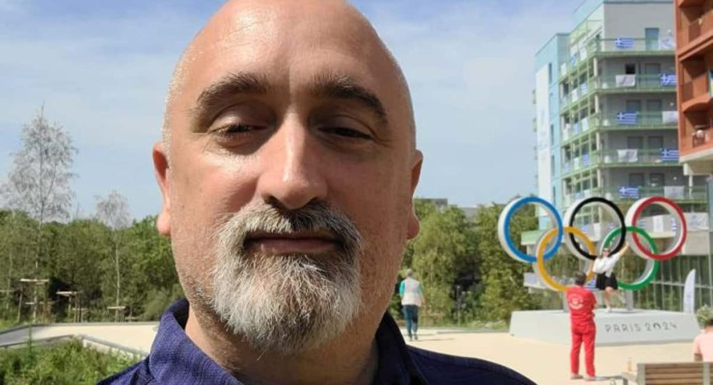 Sergi López, exnadador olímpico, se fotografía ante los anillos olímpicos de la Villa de los Juegos de París 2024