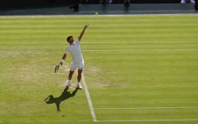 Carlos Alcaraz lanza la bola al aire para sacar sobre la hierba de la pista central de Wimbledon